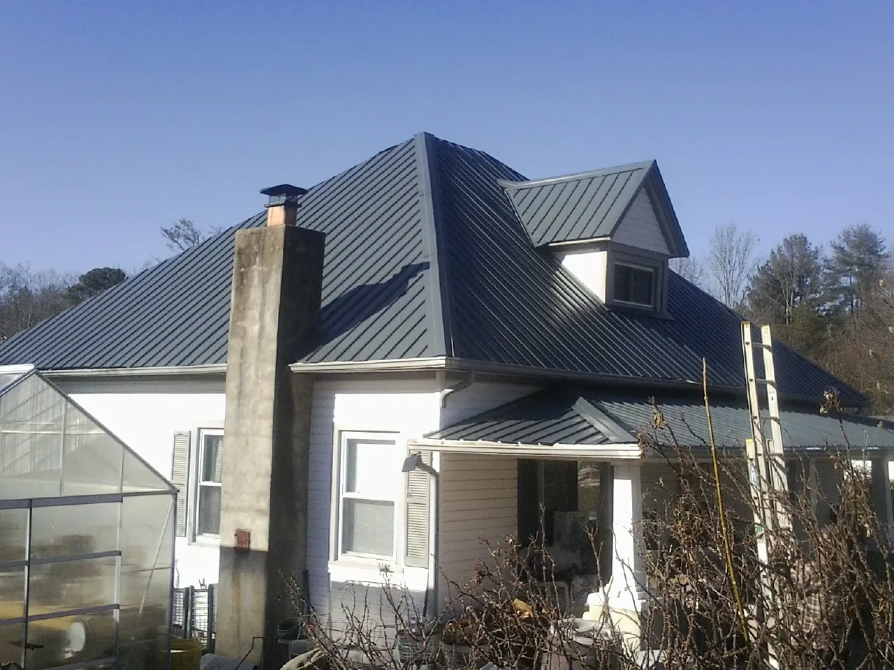 Dark blue standing seam metal roof on a white farmhouse with dormer — Slate & Tile Roof Repair by Roofing Brothers in Cayuga