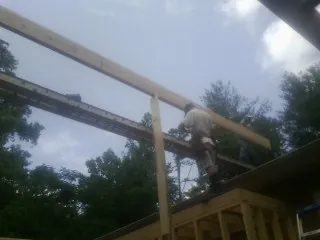 Carpenter setting a ridge beam over a new addition frame — Ice Dam Removal by Roofing Brothers in Cayuga