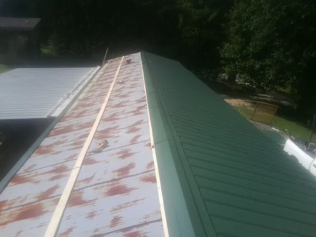 Old rusted panels beside newly installed green metal roofing — Wind Damage Roof Repair by Roofing Brothers in Cayuga