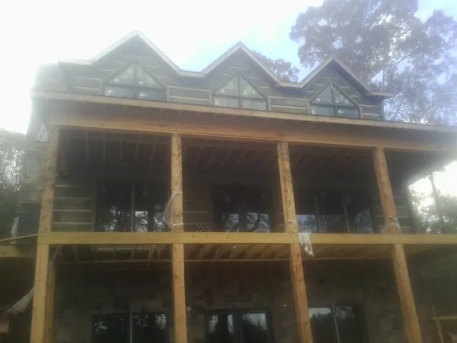 Dormers and porch framing on a large log home under construction — Roof Coating work by our crew in Cayuga
