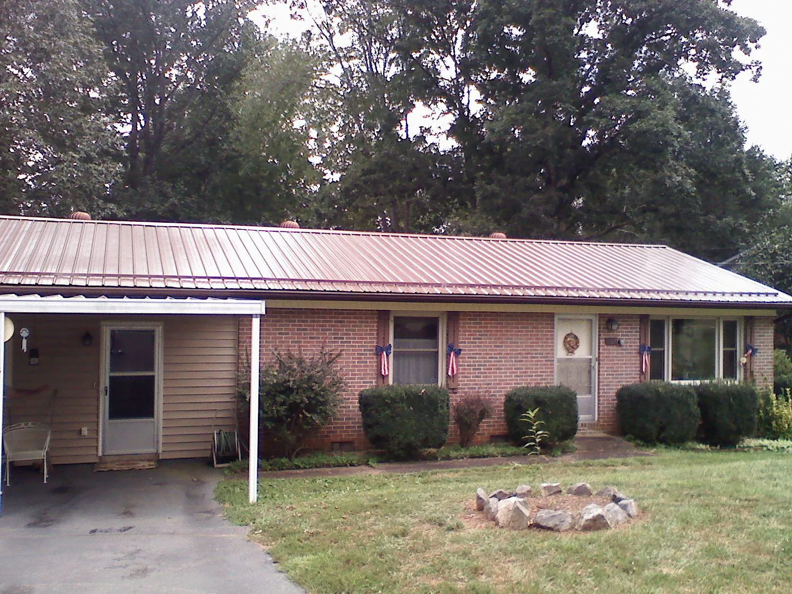 Bronze metal roof and carport on a brick ranch home — Roof Repair work by our crew in Cayuga
